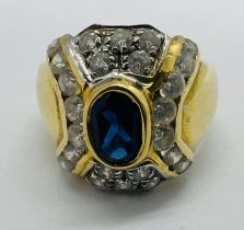 An Italian cluster ring, stamped 750 and set with a central oval shaped blue cubic zirconia and