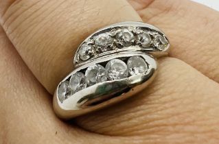 A white metal cubic zirconia set serpent form crossover ring. Featuring ten round brilliant cut