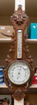 A 20th century Reynolds & Sons of London carved oak barometer with leaf design. Approx. 88cm long.