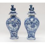 A pair of Delft lidded vases,, both with blue and white country and figural scene, floral detail and