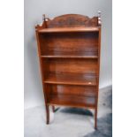 A 20th century foldable bookshelf on four feet with carved stylised part to top