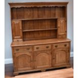 A large reproduction solid oak George III kitchen dresser with solid top, shelving, spice doors