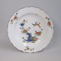 A Meissen plate, painted in Kakiemon style with a bird in flight over flowers and rockwork. Blue