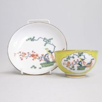 A Meissen yellow ground tea bowl and saucer, painted with a bird sitting on a pine branch, blue
