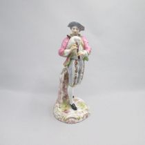 A Continental porcelain figure of a boy musician playing a bag pipe, standing on an orate gilded