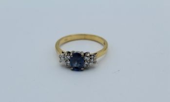 An 18k sapphire and diamond ring, the oval cut sapphire with trio of brilliant cut diamonds to