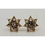 A pair of precious yellow metal diamond cluster earrings, each having star form mount set eight