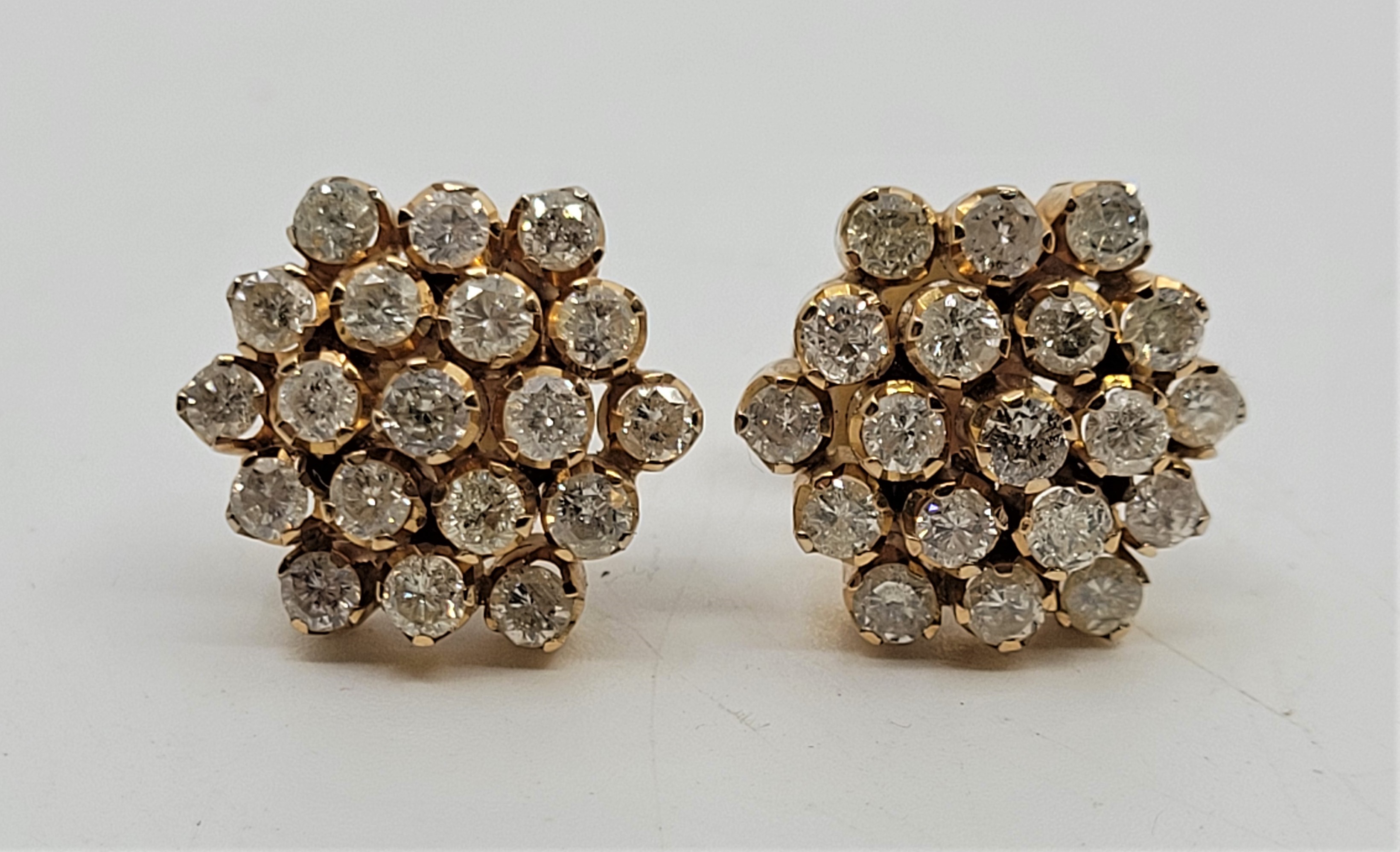 A pair of precious yellow metal diamond cluster earrings, each having domed mount set nineteen round