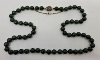 A Chinese spinach green jade necklace, with silver clasp and yellow metal security chain, length