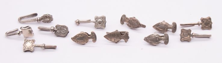 A collection of twelve early 20th Century silver napkin clips, cartouche or shield shaped with