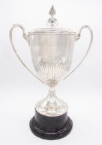 An Edwardian large two handled silver trophy and cover, loop handles, plain upper section above leaf