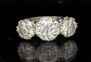 A three stone old diamond and platinum ring, comprising round brilliant cut diamonds, the