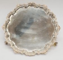 A Georgian style silver salver, raised cut card border with rocaille and foliage, on three scroll