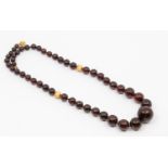 A resin type gold bead necklace, comprising graduated round beads, the largest to the front