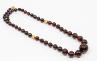 A resin type gold bead necklace, comprising graduated round beads, the largest to the front