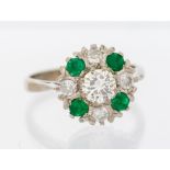 An emerald and diamond 18ct white gold cluster ring, comprising a central round brilliant cut