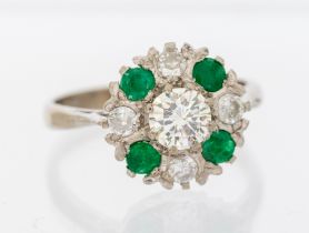 An emerald and diamond 18ct white gold cluster ring, comprising a central round brilliant cut