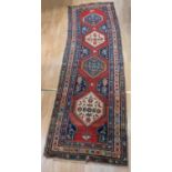 A Persian wool runner (mid 20th Century, Iranian) handwoven, red ground decorated with motifs and