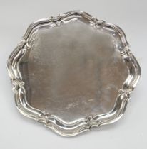 A George V large silver salver, shaped octagonal with raised border on four stylised hoof
