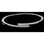 A diamond and 14ct white gold cross over bangle, comprising five round brilliant cut channel set
