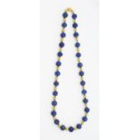 A lapis lazuli and gold bead pendant, comprising round carved beads with carved decoration, possibly