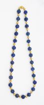 A lapis lazuli and gold bead pendant, comprising round carved beads with carved decoration, possibly