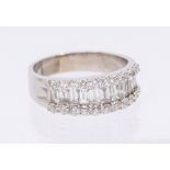 A diamond and 18ct white gold ring, comprising a central channel set row of eleven tapering baguette