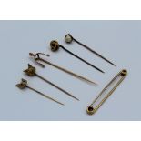 A 9ct gold stock pin, a 9ct gold fox mask stick pin and four unmarked yellow metal stick pins,