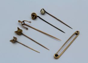 A 9ct gold stock pin, a 9ct gold fox mask stick pin and four unmarked yellow metal stick pins,