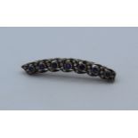 An Edwardian 9ct gold, silver, diamond and sapphire set brooch of slight bow form. The seven