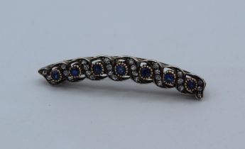 An Edwardian 9ct gold, silver, diamond and sapphire set brooch of slight bow form. The seven