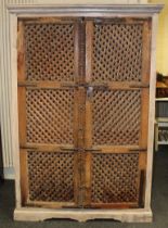 A painted hardwood cupboard, having a pair of Asian influence slatted metal bound panel doors,