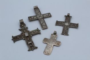 A collection of four crosses. Two pieces, in unmarked white metal featuring detailed wire work,
