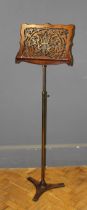 An Edwardian walnut music stand, the serpentine, adjustable pierced rest on a telescopic brass