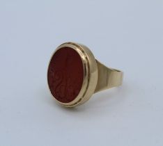 An unmarked yellow seal ring, featuring a large closed back Carnelian Intaglio engraved with a stags