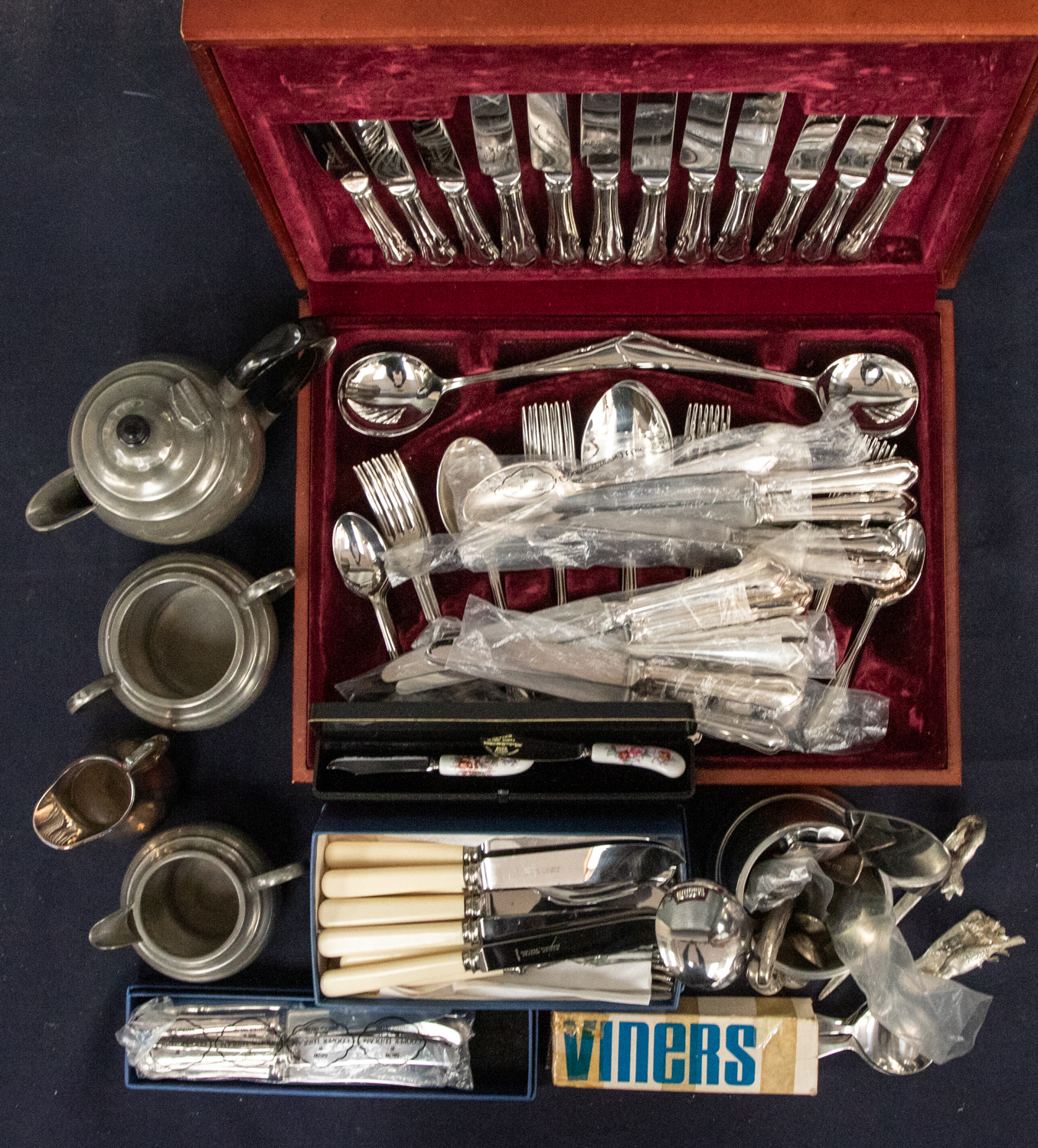 A mid 20th century full canteen of cutlery, unused, along with a hammered pewter tea set, c.1900,