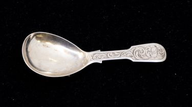 A Victorian silver fiddle pattern caddy spoon, the handle engraved with swirling foliage, with