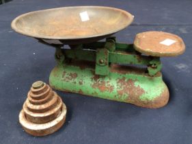 A set of green painted kitchen scales with dish and five weights (some rusting and wear)
