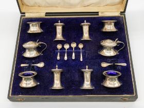 A cased mixed George V silver double condiment set consisting of two mustard pots with blue glass