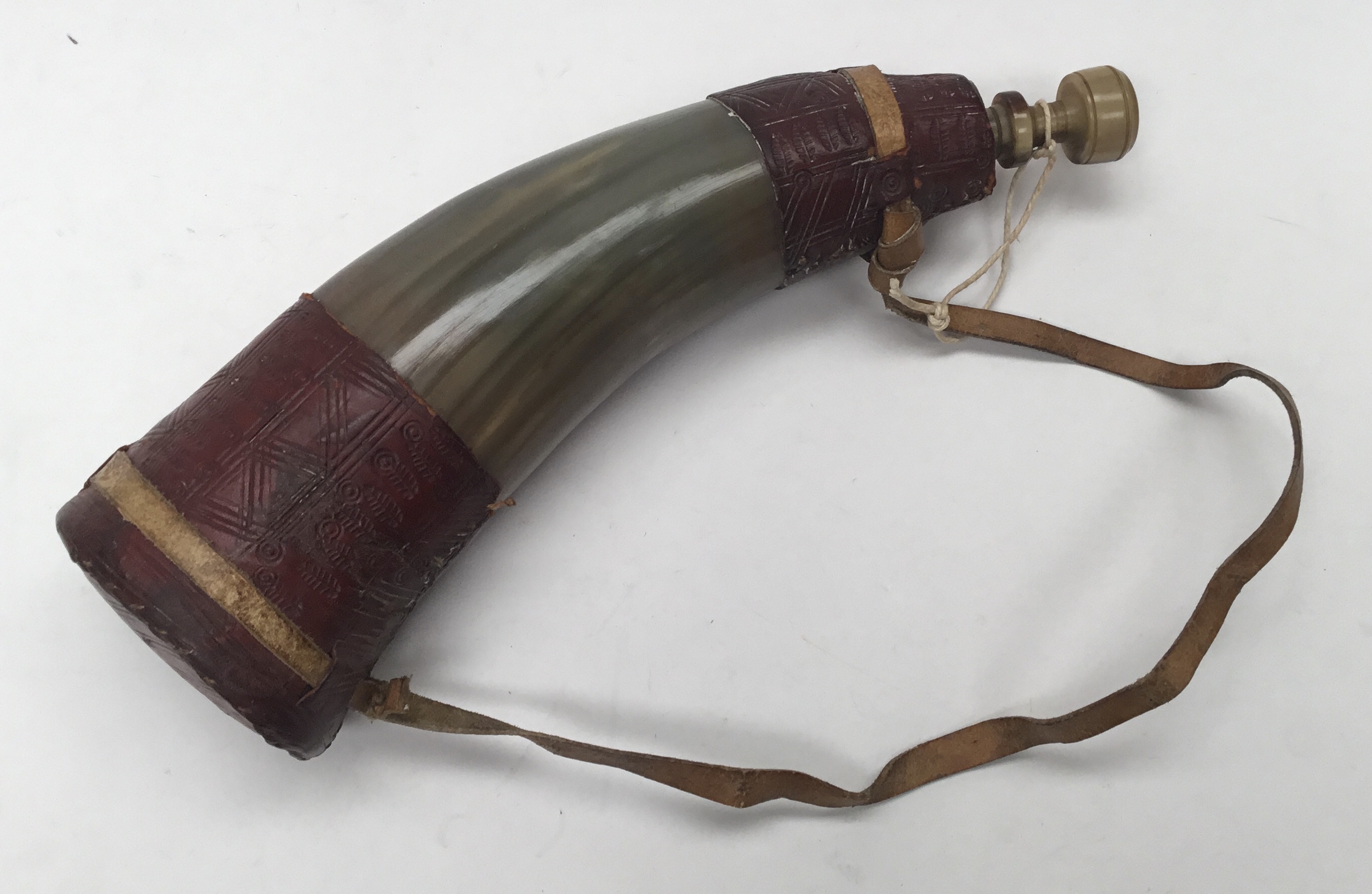 A vintage leather bound powder horn. Cattle horn body with maroon tooled leather mounts to both