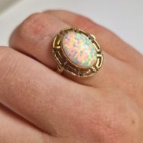 Oval opal ring. A single opal set in a Grecian design setting of 14ct gold (marked 585). Opal