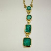 An emerald and 18ct yellow gold pendant. Four graduating emerald cut emeralds set in an 18ct