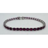 ***** AWAY TO VENDOR**** A ruby line bracelet featuring 38 oval mixed cut rubies, set into white