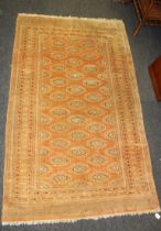 Two similar 20th century loom woven Bokhara type wool rugs, each with guls, on a pale salmon ground.