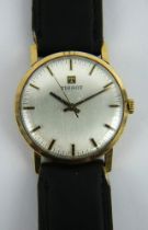 A 9ct gold cased 1970s Tissot wristwatch on black leather strap. Silver dial with black indices.