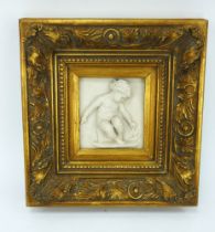 A rococo style parian ware plaque of a putti playing with a boat, mounted in a deep gilt frame.