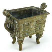 A brass Chinese censer of rectangular form, raised on four legs and with dragon handles.