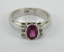 White gold ring with central ruby set amid four diamonds. Shank marked 18ct. Size L