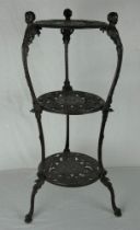 A vintage cast iron three tier kitchen pot/saucepan stand with figural uprights. Overall height 76cm