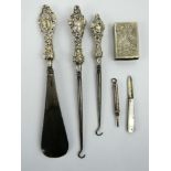 Two silver handled buttons hook, a shoe horn, silver pencil, silver fruit knife & a plated vesta.